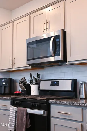 a kitchen with stainless steel appliances granite countertop white cabinets and a microwave oven