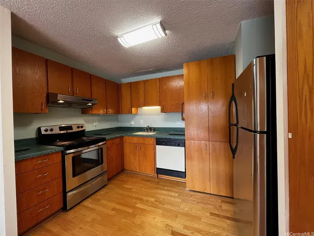 a kitchen with stainless steel appliances granite countertop a refrigerator a sink and a stove