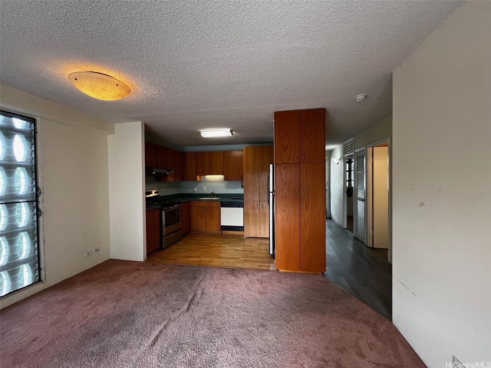 1615 Wilder Avenue, Unit 607 Honolulu, HI 96822 - Photo 4 of 19 an empty room with a kitchen and windows