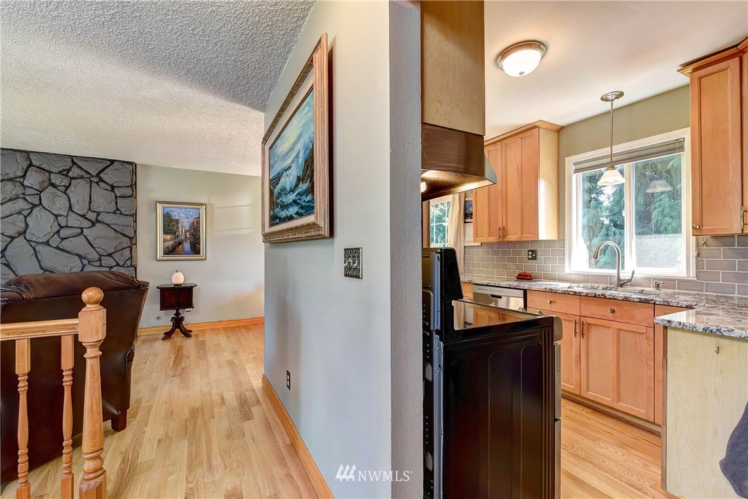 110 217th Place Southeast Bothell, WA 98021 - Photo 6 of 32 a kitchen with stainless steel appliances granite countertop a refrigerator a sink dishwasher a stove and white countertops with wooden floor