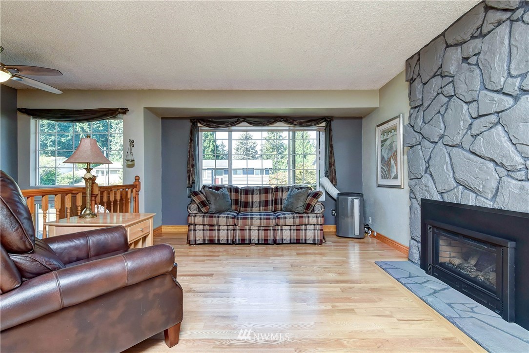 110 217th Place Southeast Bothell, WA 98021 - Photo 9 of 32 a living room with furniture a fireplace and a floor to ceiling window