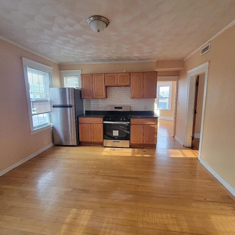 111 Rodney Street, Unit 2 Worcester, MA 01605 - Photo 2 of 9 a view of a kitchen with a stove cabinets and a wooden floor