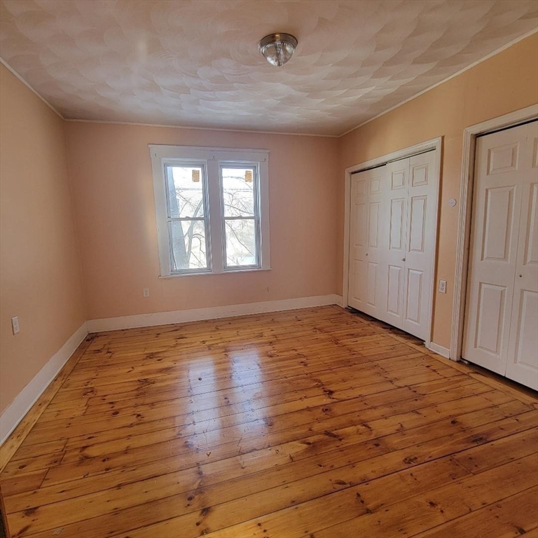 111 Rodney Street, Unit 2 Worcester, MA 01605 - Photo 5 of 9 an empty room with wooden floor and windows