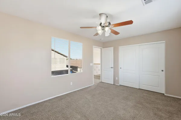 an empty room with closet and a chandelier fan
