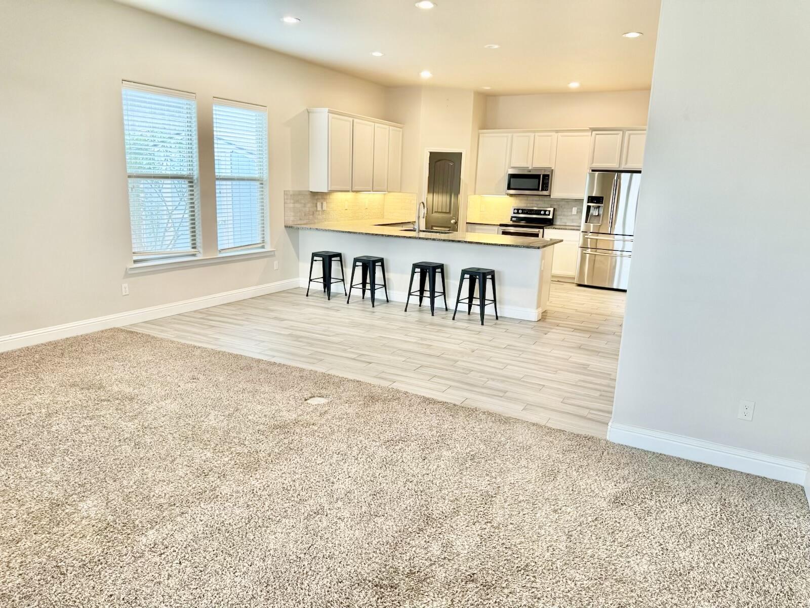 13801 Avenue West Lubbock, TX 79423 - Photo 16 of 17 a kitchen with stainless steel appliances kitchen island granite countertop a stove a sink and a microwave
