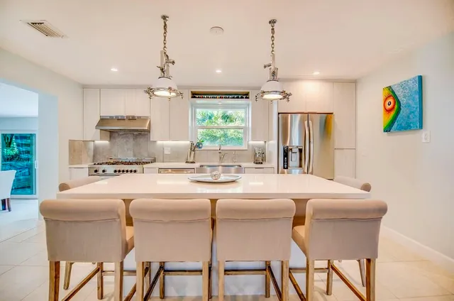a kitchen with a dining table chairs stainless steel appliances and chandelier