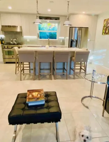 a kitchen with stainless steel appliances kitchen island granite countertop a table chairs and a refrigerator