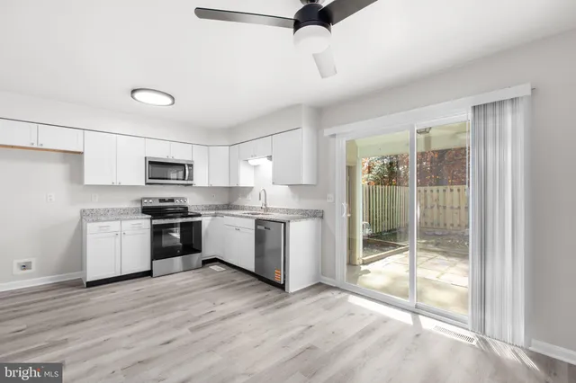 a kitchen with stainless steel appliances kitchen island wooden cabinets and view of living room