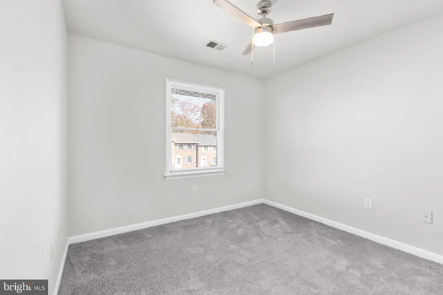 an empty room with a window and a fan