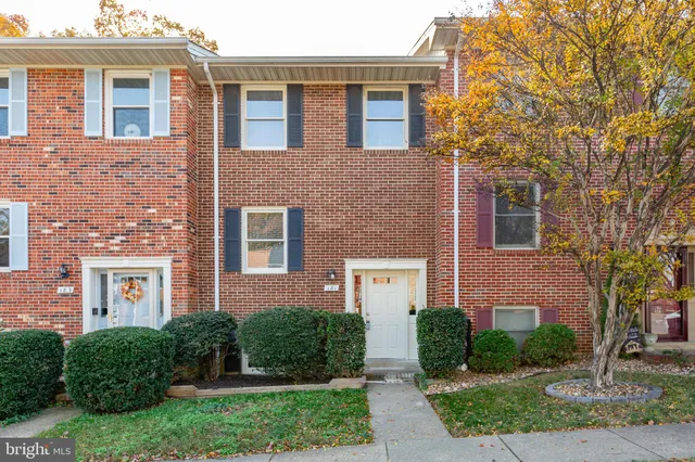 front view of a brick house with a yard and large trees