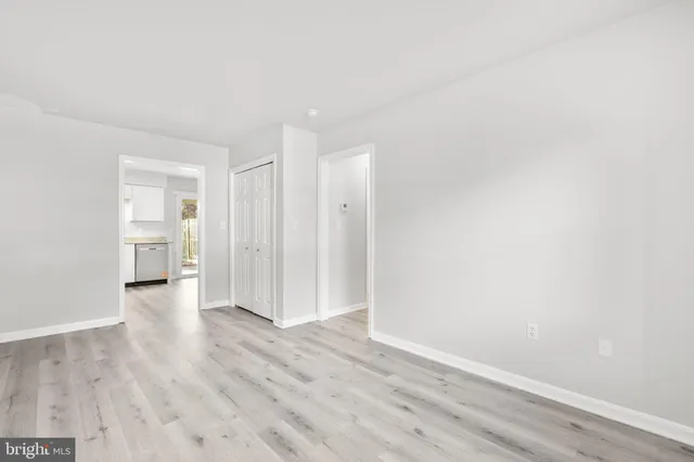 a view of an empty room with wooden floor and closet