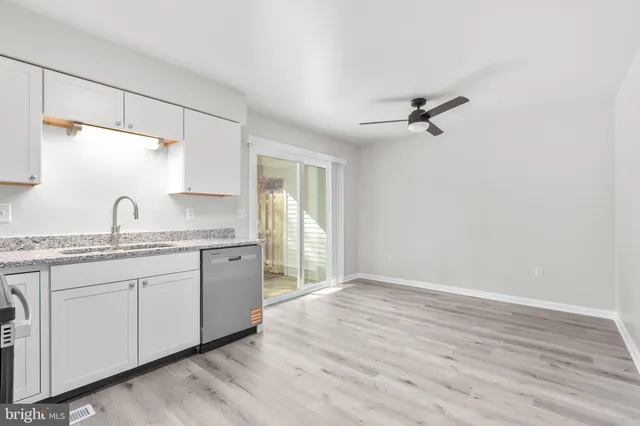 a kitchen with granite countertop a sink cabinets stainless steel appliances and a window