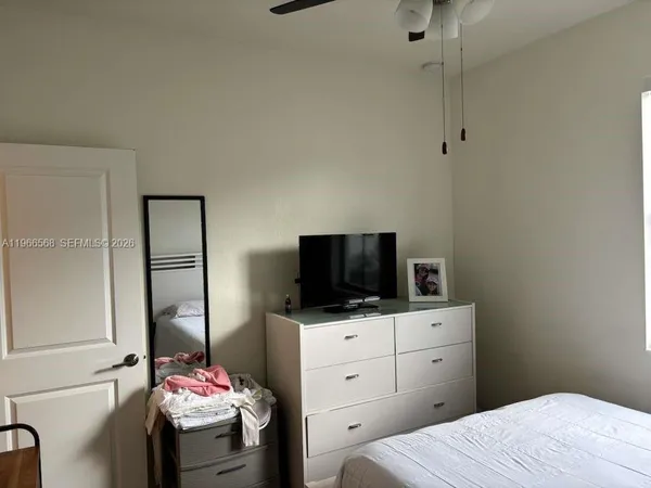 a bedroom with a bed and a flat tv screen on dresser