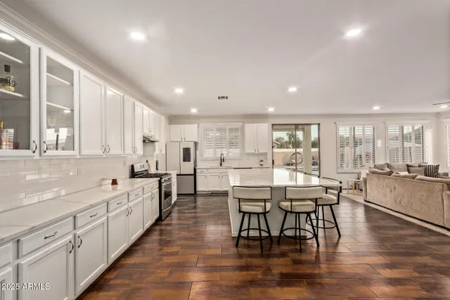 a kitchen with stainless steel appliances kitchen island granite countertop a table chairs sink and cabinets