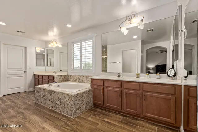 a spacious bathroom with a double vanity sink mirror and bathtub