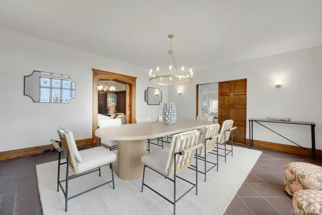 a dining room with wooden floor a chandelier a glass table and chairs