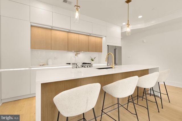 a large white kitchen with a large window a sink and stainless steel appliances