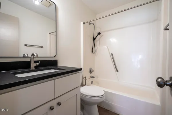 a bathroom with a granite countertop sink a toilet a mirror and shower