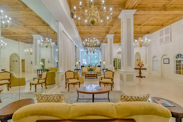 a living room with couches and kitchen view with chandelier