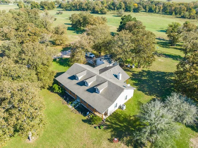 a view of a lake with lawn chairs and large trees