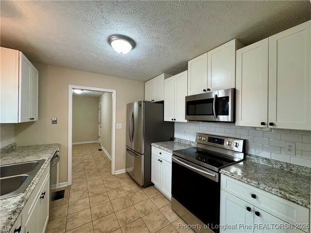 a kitchen with stainless steel appliances a stove a sink a microwave a refrigerator and cabinets