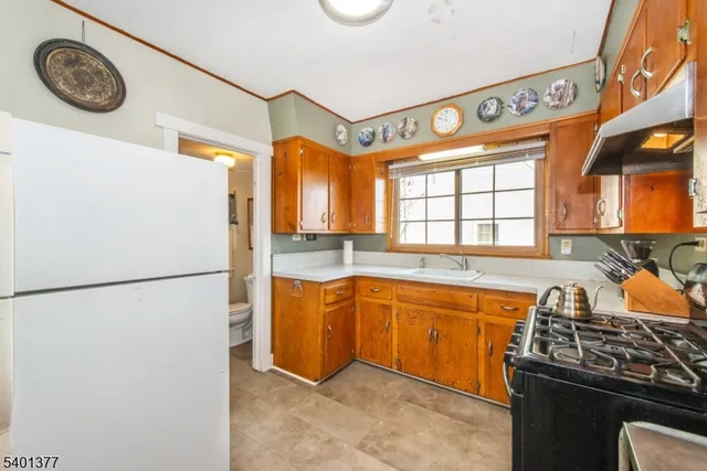 a kitchen with stainless steel appliances granite countertop a refrigerator a sink a stove and a refrigerator