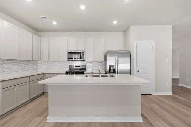 a kitchen with kitchen island sink stove and cabinets