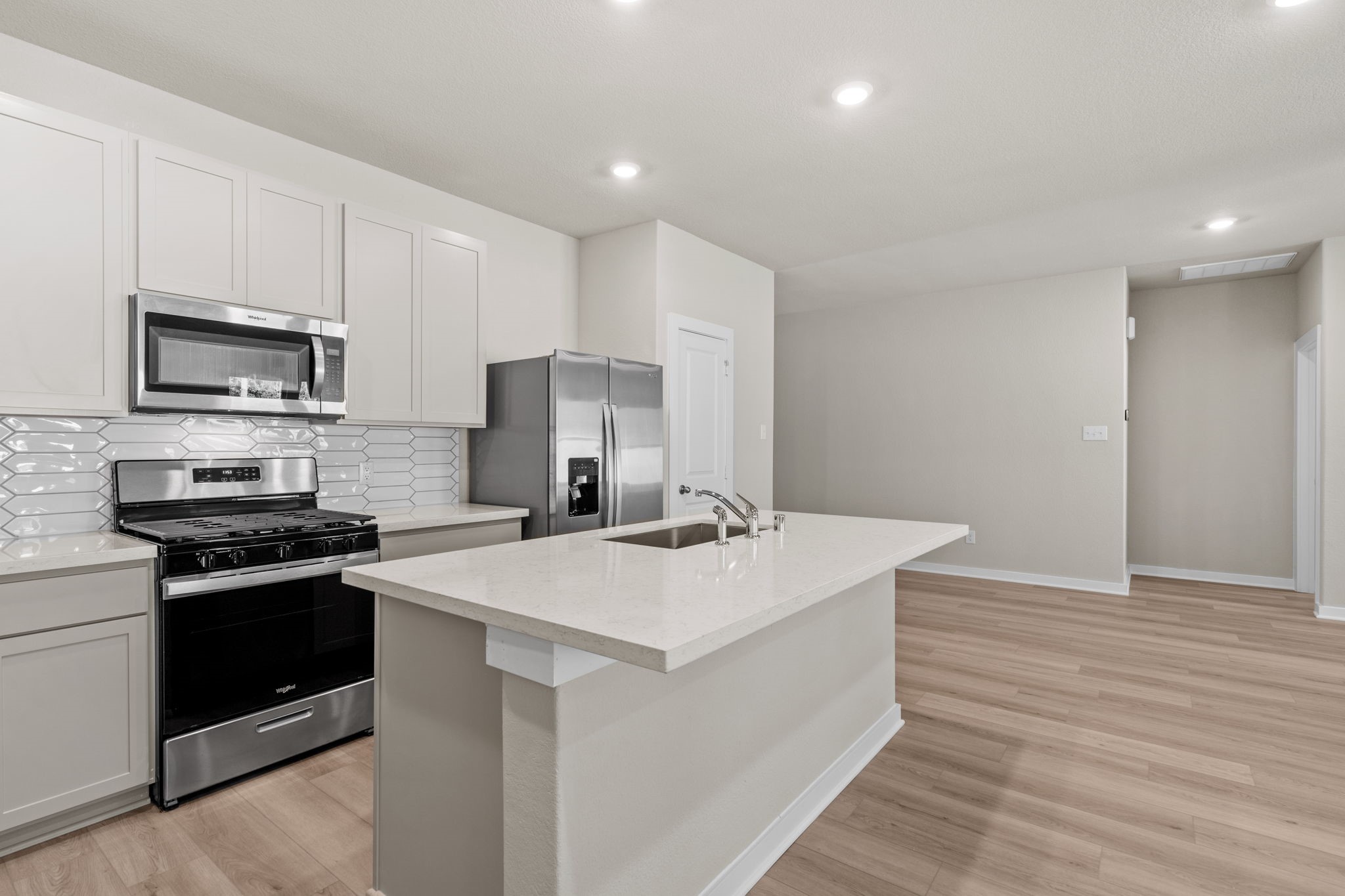 12343 Ridge Top Drive Conroe, TX 77304 - Photo 7 of 32 a kitchen with stainless steel appliances a stove top oven a sink dishwasher and a refrigerator with wooden floor