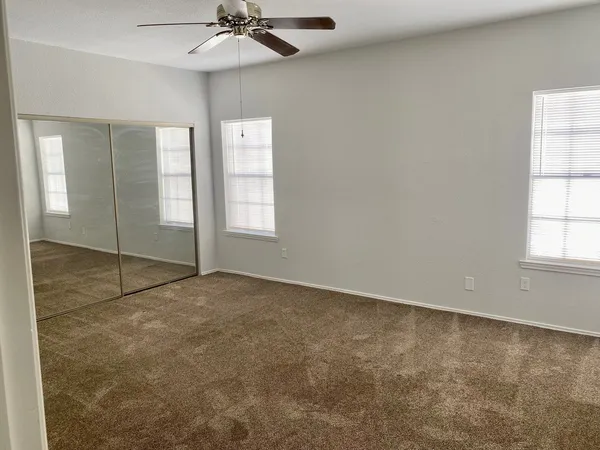 an empty room with windows and chandelier fan