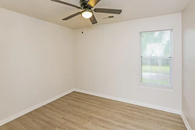 an empty room with a window and a fan