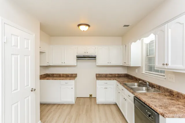 a kitchen with stainless steel appliances granite countertop a stove a sink and white cabinets