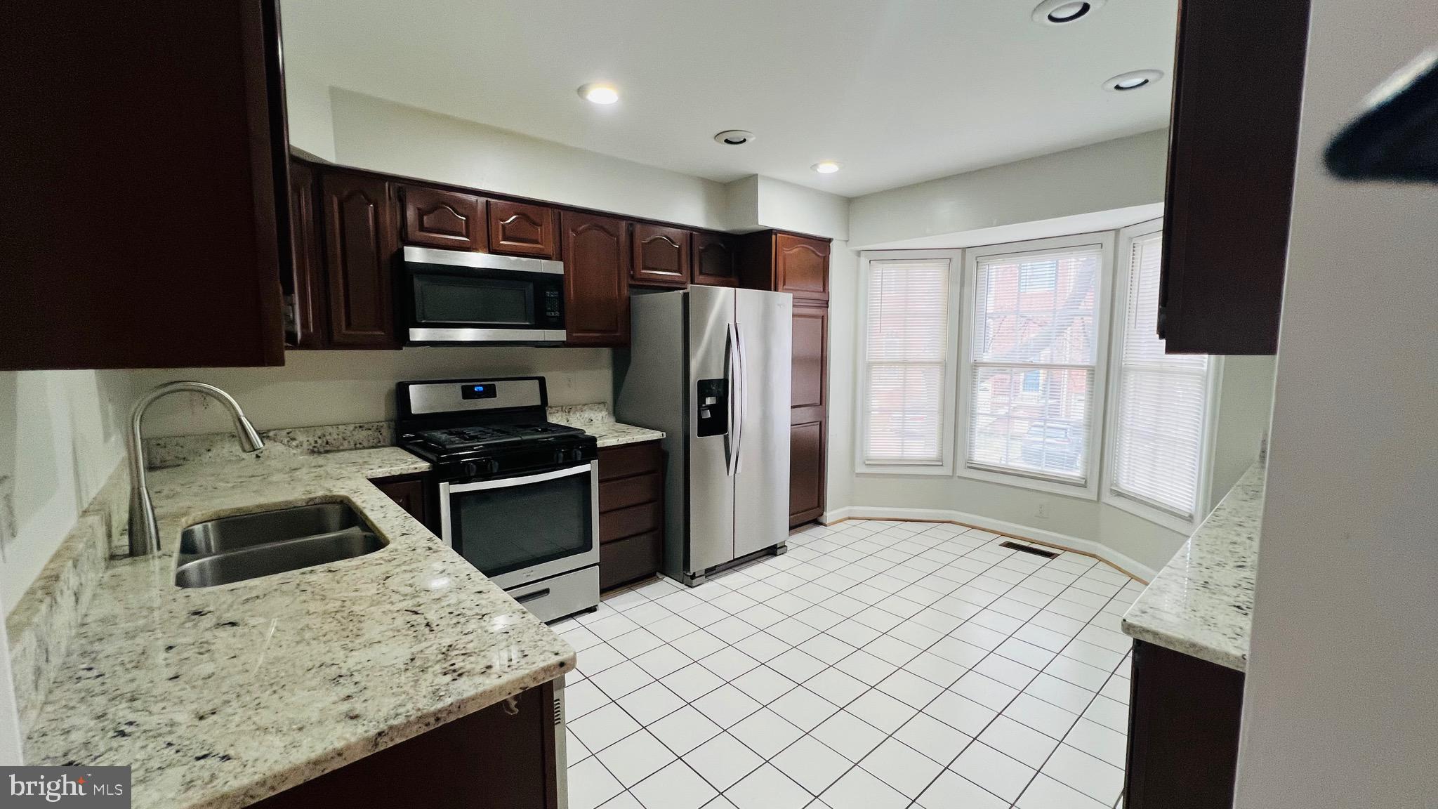8035 Trevor Place Vienna, VA 22182 - Photo 30 of 48 a kitchen with stainless steel appliances kitchen island granite countertop a sink stove and refrigerator