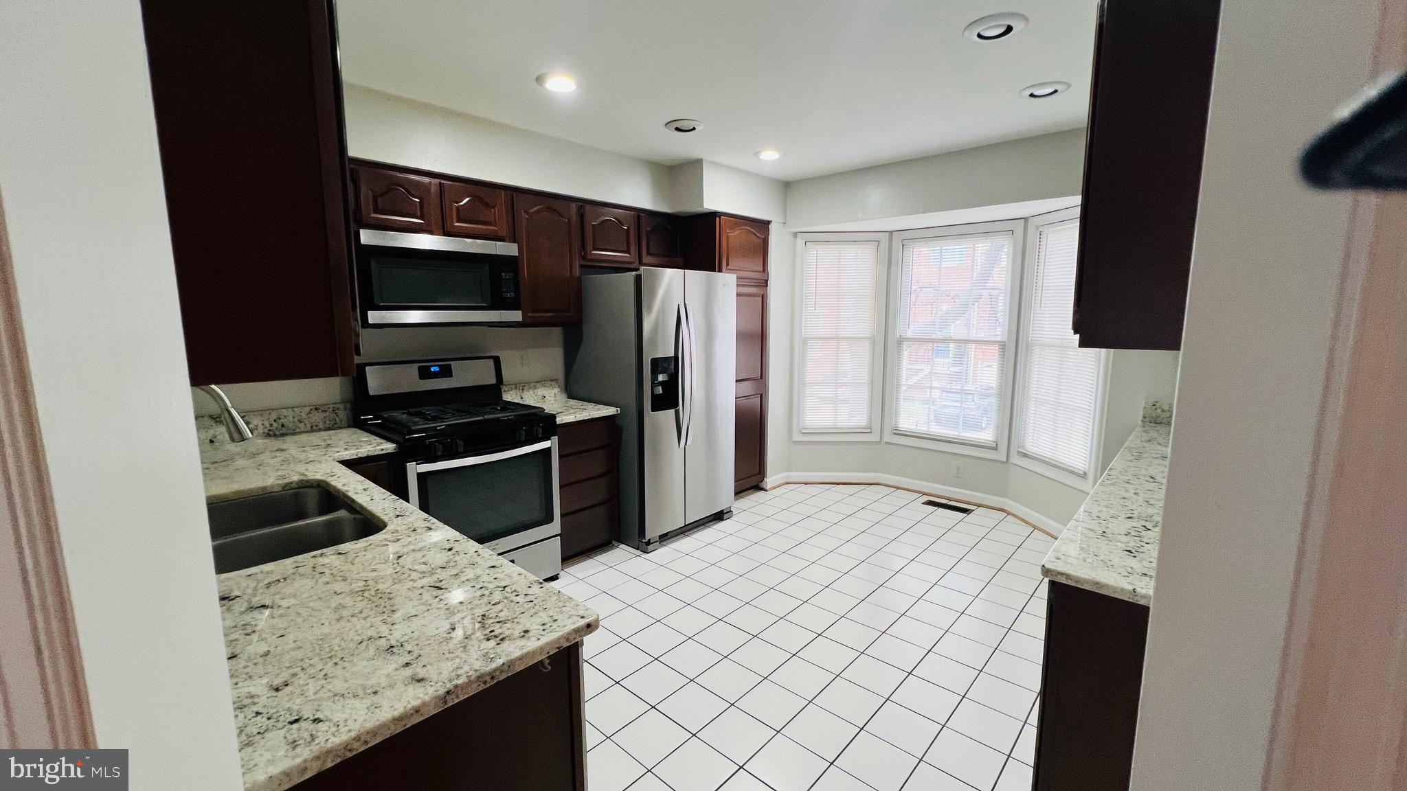 8035 Trevor Place Vienna, VA 22182 - Photo 31 of 48 a kitchen with stainless steel appliances kitchen island granite countertop a refrigerator and a sink