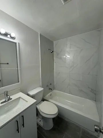 a bathroom with a granite countertop bathtub shower sink vanity and toilet