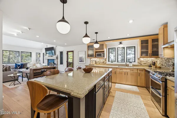 a kitchen with granite countertop a stove a sink a dining table and chairs
