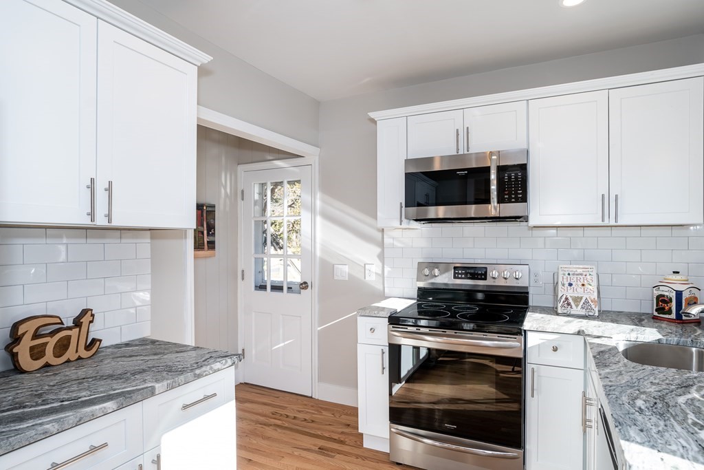 a kitchen with granite countertop a sink a stove and microwave