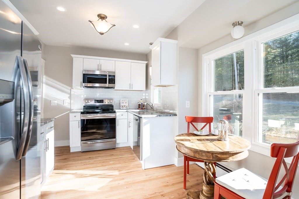 252 Old Warren Road Palmer, MA 01069 - Photo 2 of 29 a kitchen with a sink a stove a refrigerator cabinets and a dining table with wooden floor