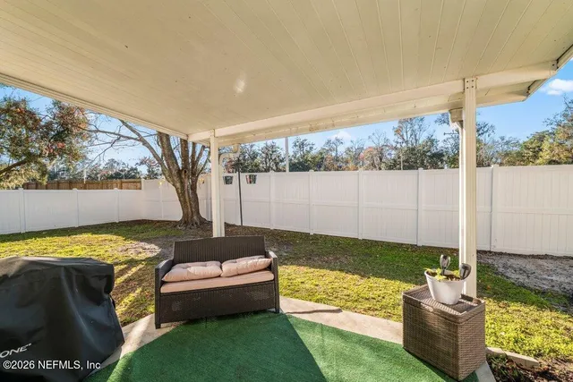 a view of a backyard with couches plants and large trees