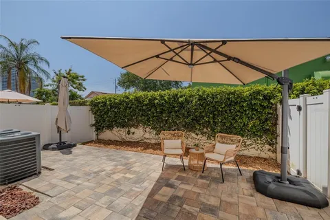 a backyard of a house with table and chairs under an umbrella
