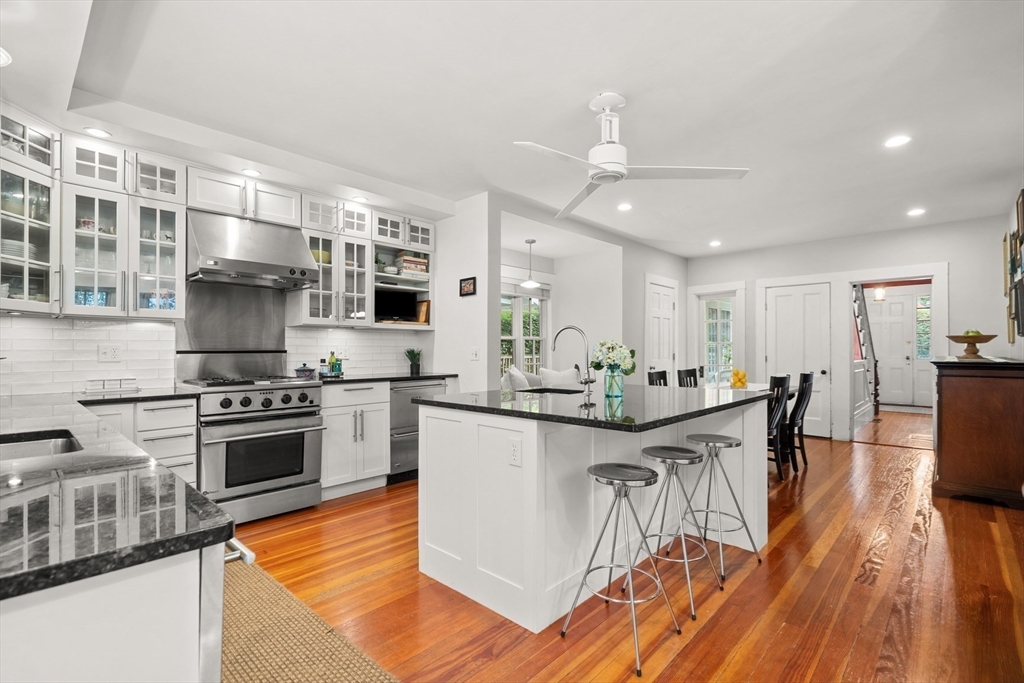 104 Church Street Winchester, MA 01890 - Photo 11 of 42 a kitchen with stainless steel appliances granite countertop a stove top oven a sink dishwasher a dining table and chairs with wooden floor