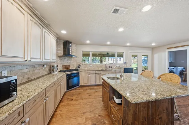 a kitchen with granite countertop kitchen island stainless steel appliances a sink stove and cabinets