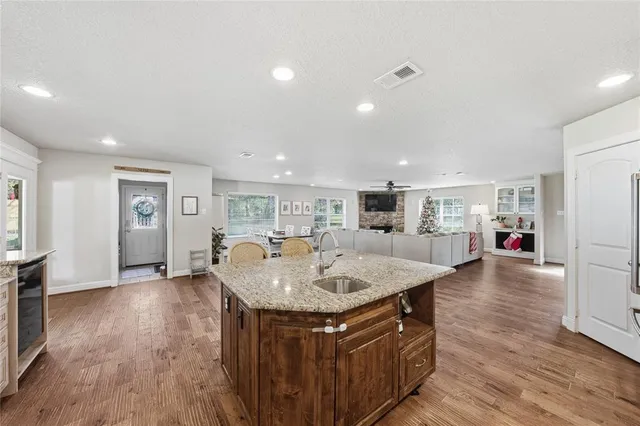 a view of kitchen island a sink wooden floor and a living room