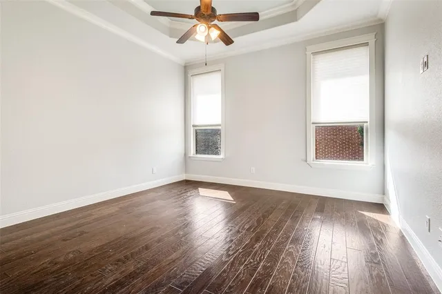 an empty room with wooden floor chandelier fan and windows