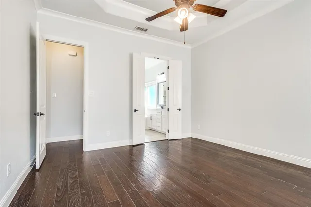 an empty room with wooden floor and a ceiling fan
