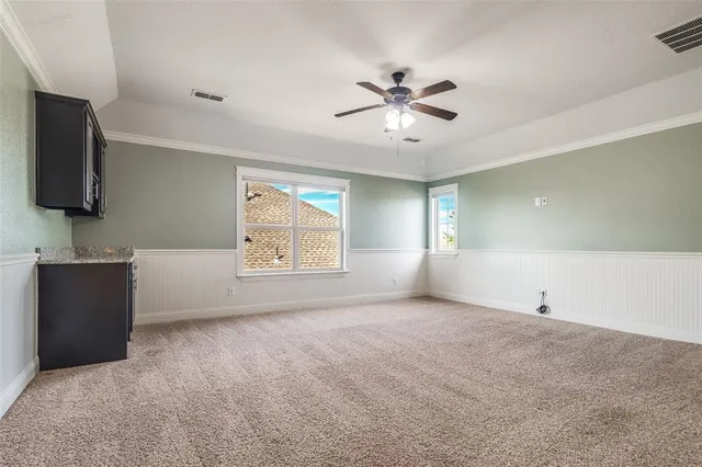 a view of an empty room with window and a kitchen