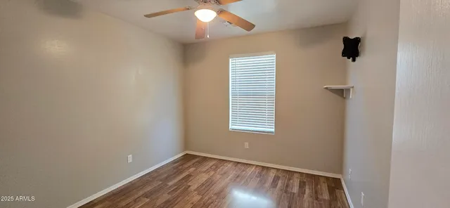 an empty room with a chandelier fan and windows