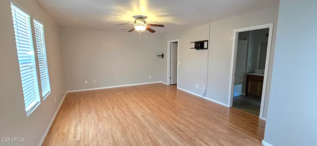 a view of an empty room with a window and wooden floor