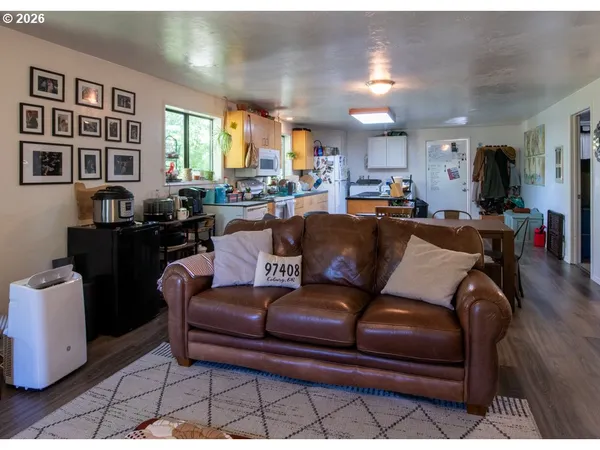 a living room with furniture a large window and wooden floor