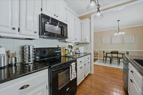 a kitchen with stainless steel appliances a stove a sink and white cabinets