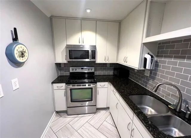 a kitchen with granite countertop a stove a sink and a microwave